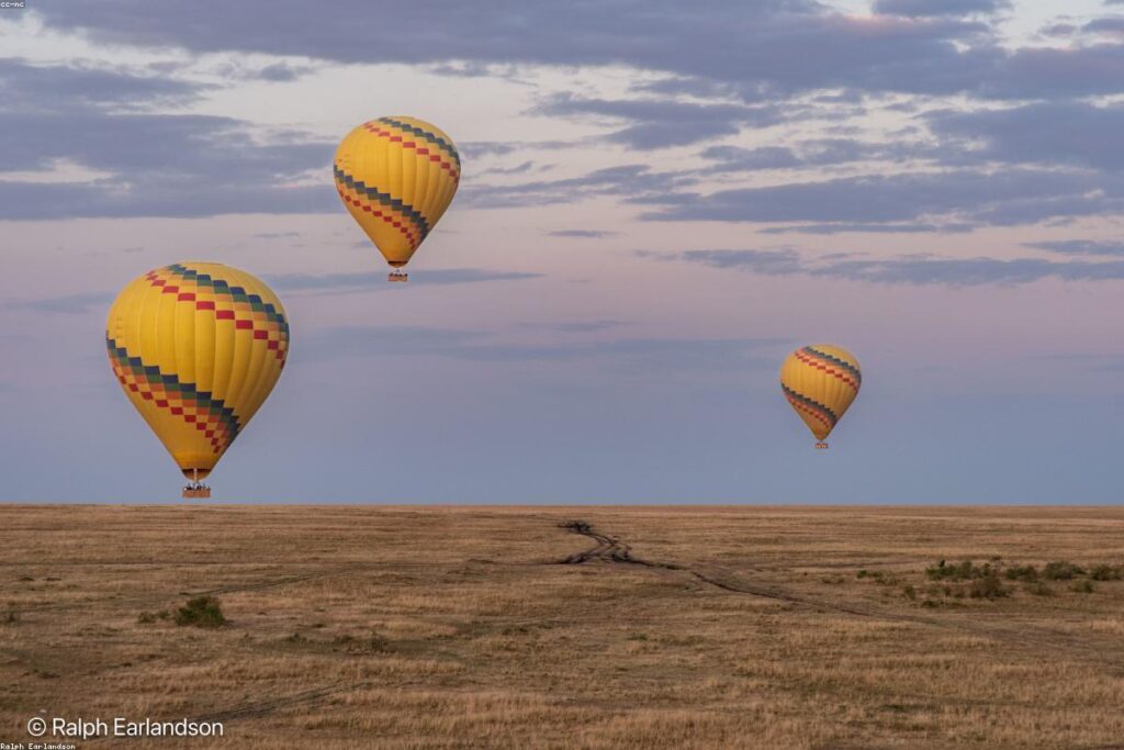 Hot air balloons flying over San Miguel de Allende at sunrise with colonial city and mountains below